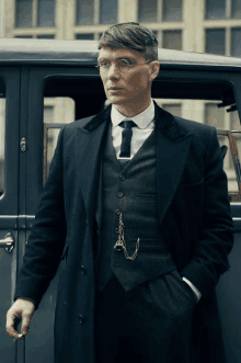 a man in a suit and tie standing next to a car