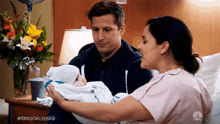 a man and woman are holding a baby in a hospital room .