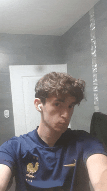 a young man taking a selfie in a bathroom with a rooster on his shirt