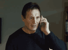 a man in a black sweater is talking on his cell phone