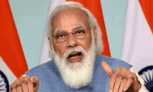 a man with a beard and glasses is giving a speech in front of a flag .