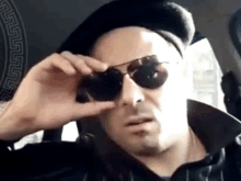 a man wearing a beret and sunglasses is looking through his glasses