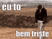 a man is walking in the desert with the words eu to bem triste written on the ground .