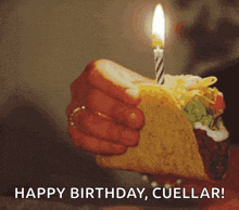 a person is holding a taco with a candle and the words happy birthday cuellar