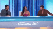 a group of people are sitting at a table with a sign that says american idol .