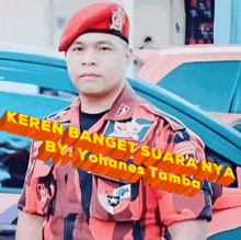 a man wearing a red beret stands in front of a car with the words " keren banget suaranya " on the bottom