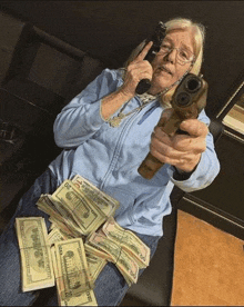 an elderly woman is sitting on a couch holding a gun and a pile of money .