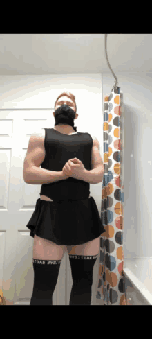 a man standing in front of a shower curtain wearing a black skirt