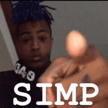 a man with blue hair is pointing at the camera and the word simp is on the bottom