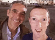 two men are posing for a selfie together and smiling .