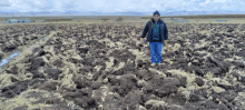 a man stands in a field of dirt and grass