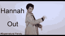 a man in a trench coat is standing in front of a white wall with hannah out written on it