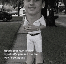 a man with a big head is standing on a sidewalk in a park .