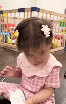 a little girl with a flower in her hair is sitting on the floor looking at something