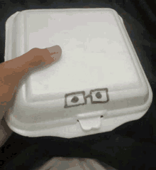 a person is holding a styrofoam container with a drawing of a pair of glasses on it .