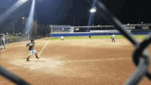 a baseball game is being played on a field with a fence in the foreground and a few players on the field