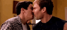 a couple of men are kissing each other in a living room .