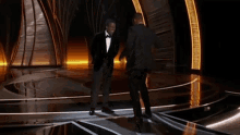 two men in tuxedos are dancing on stage