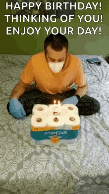 a man wearing a mask and gloves is sitting on a bed with a birthday cake made out of toilet paper