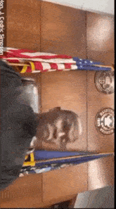 a man in a black shirt is standing in front of a wall with flags and badges on it ..