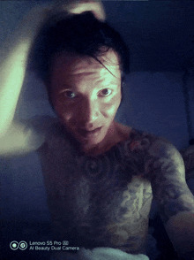 a man with a tattoo on his chest is taking a selfie with a lenovo s5 pro