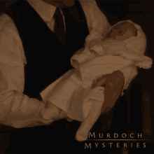 a man is holding a baby in his arms with murdoch mysteries written on the bottom