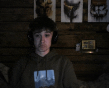 a young man wearing headphones and a sweatshirt with a picture of a mountain on it