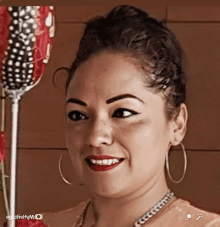 a woman wearing hoop earrings and a necklace is smiling and looking at the camera