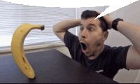 a man sitting at a table with his mouth open and a banana on the table