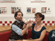 a man and a woman are drinking from paper cups in front of a sign that says weekender va 2013