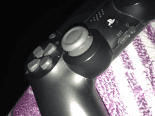 a close up of a playstation controller on a purple blanket