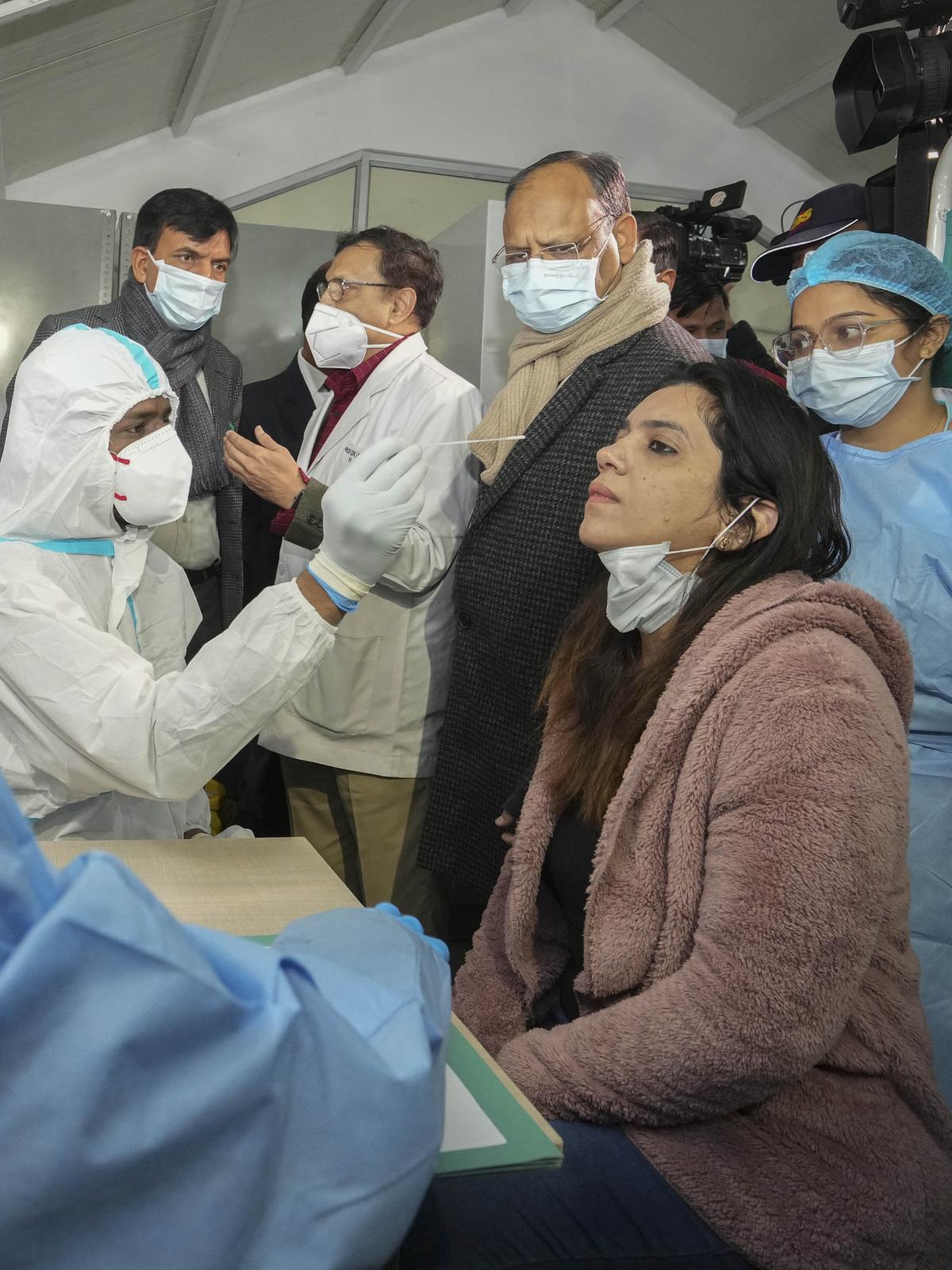 Union Health Minister Mansukh Mandaviya speaks with a doctor as a medic collects swab sample of a woman, during a nationwide mock drill for COVID-19 preparedness, at Safdarjung hospital in New Delhi on Tuesday. 