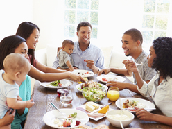 bebé en brazos de su papá, comiendo con la familia