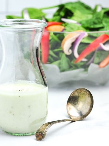 A Weck jar with Greek yogurt Gorgonzola dressing and a salad in the background.