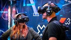 Zwei Personen mit VR-Headsets erleben eine virtuelle Realität vor einem digitalen Hintergrund.