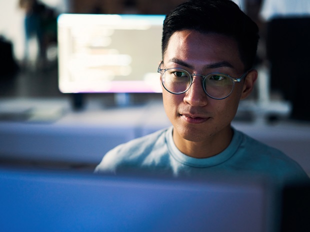 A programmer using a computer to write code in an office setting at nighttime