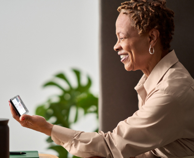 A smiling woman holding her mobile phone in her hands while having a video call