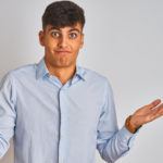 Man shrugging in front of a grey wall