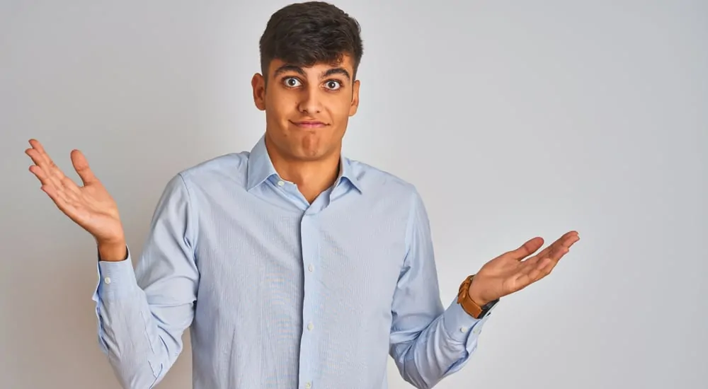 Man shrugging in front of a grey wall