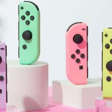 the pastel nintendo switch joy-cons upright on white and clear stands against a pink backdrop