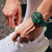 A person wearing a Samsung Galaxy Watch 7 while tying their shoe.