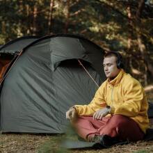 Man listening to headphones outside tent