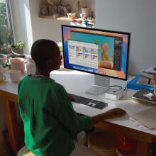 Person sitting at computer desk using Mac Mini and iMac