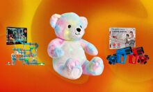 A multicolored bear, marble set, and laser tag set appear on an abstract black background.