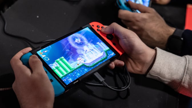 Two men use an Oled model Nintendo Switch gaming system while playing video games at the Japanese publisher Nintendo Switch's stand during Milan Games Week 2023