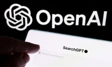 This image shows a close-up of a smartphone screen displaying the text “SearchGPT”; In the background, the OpenAI logo is prominently displayed,