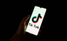 This photograph taken on April 19, 2024 shows a man holding a smartphone displaying the logo of Chinese social media platform Tiktok in an office in Paris