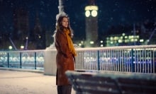 Keira Knightley stands beside the Thames in the snow with Big Ben in the background in a still from "Black Doves."