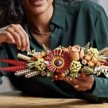 person sitting at table holding completed lego icons dried flower centerpiece