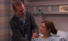 A male lactation nurse helping a woman who's sitting in a hospital bed.